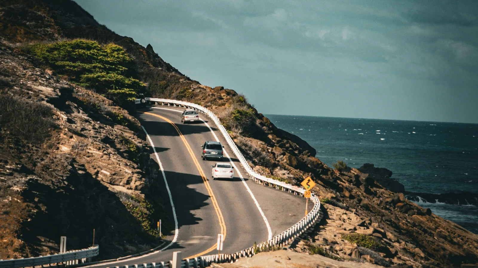 Cars traveling on a paved coastal highway in Hawaii