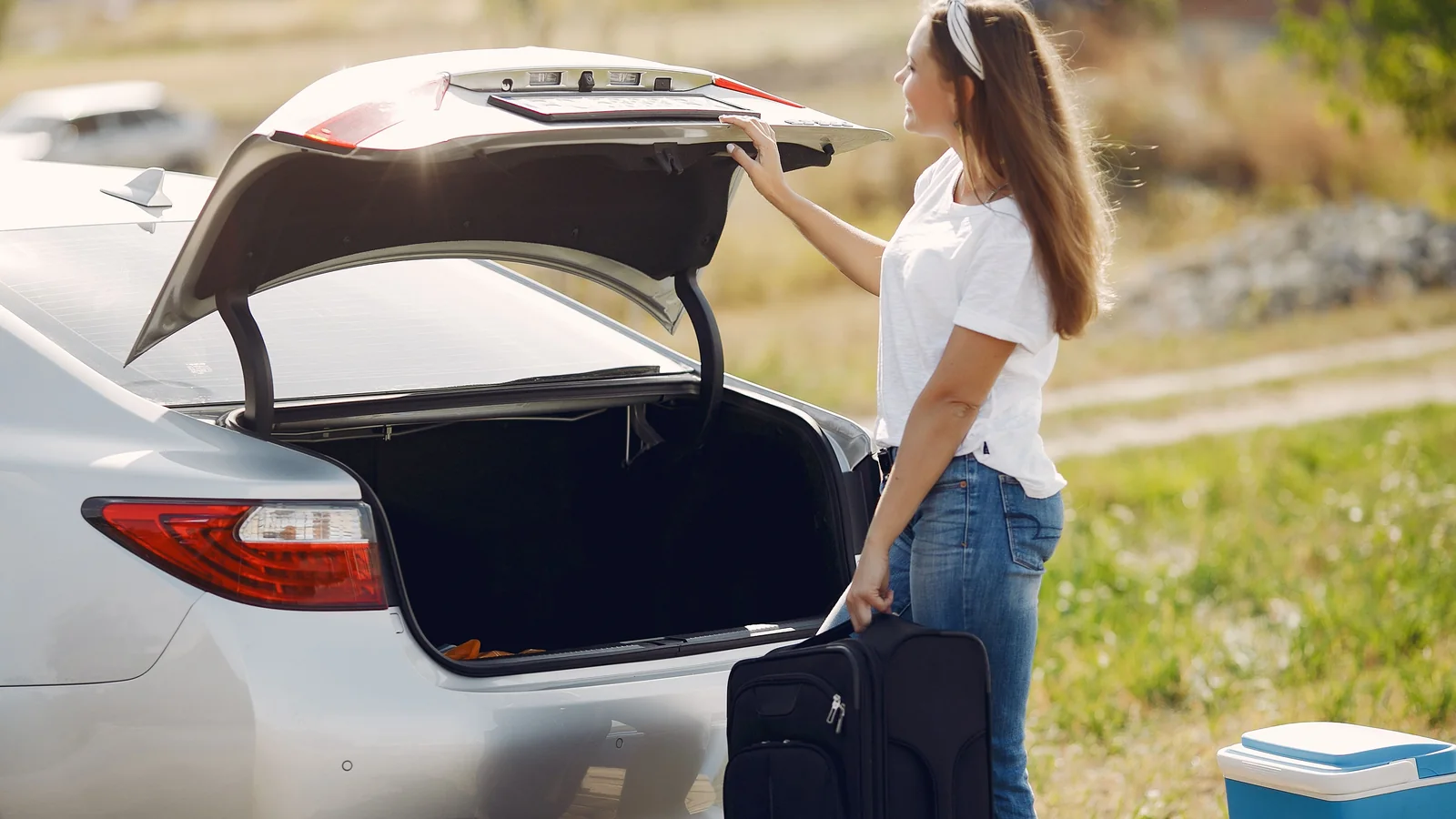 Traveler loading a suitcase into the trunk of a rental car